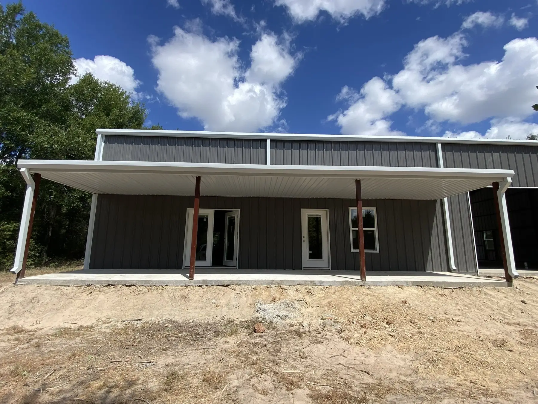 Cream barndominium with a full-length porch — built by Rodriguez Metal Buildings, Central Texas