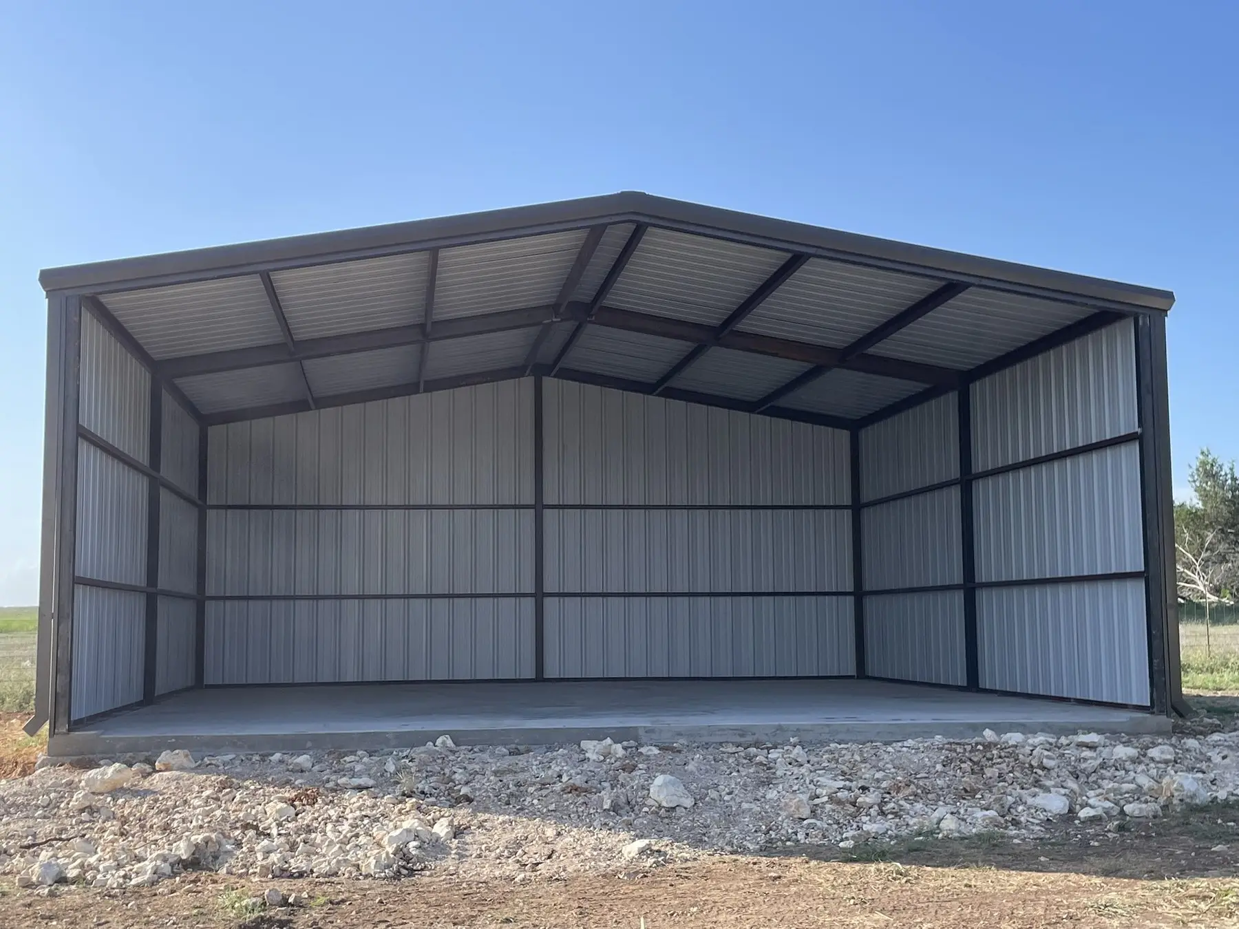 Open carport on a gravel pad — built by Rodriguez Metal Buildings, Central Texas