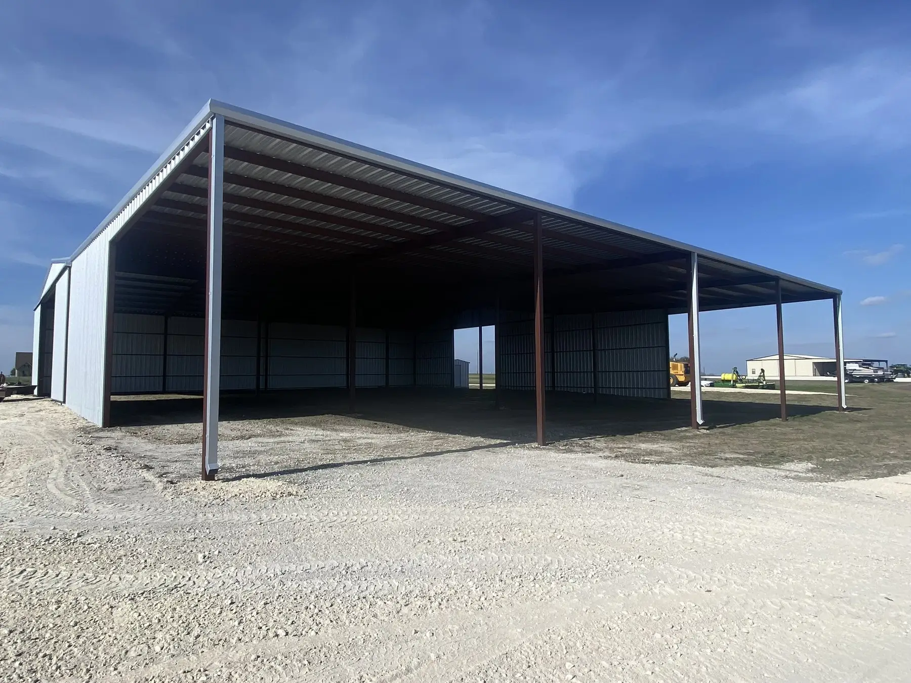 Wide equipment cover on a gravel yard — built by Rodriguez Metal Buildings, Central Texas