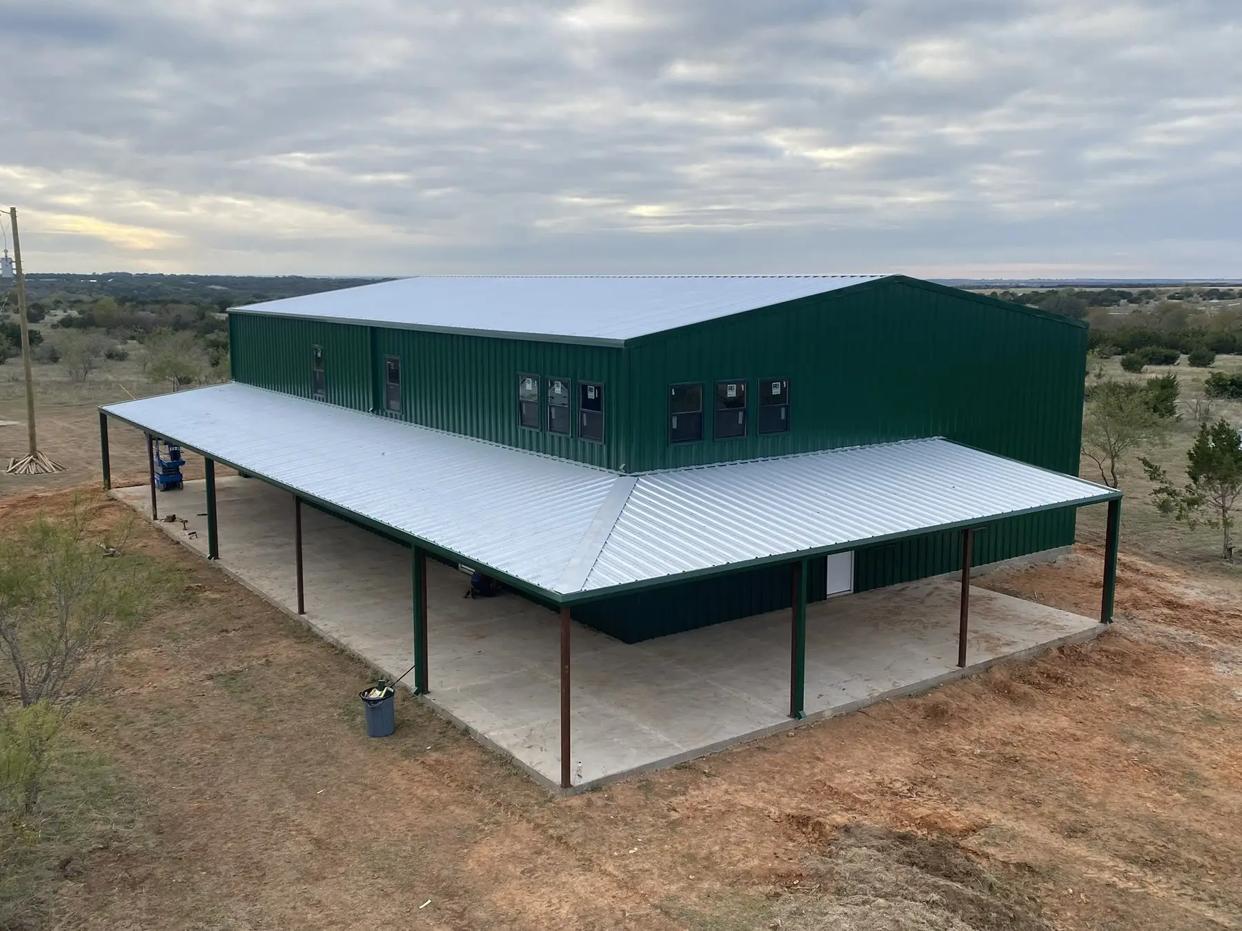 Green commercial building with a wrap-around porch — built by Rodriguez Metal Buildings, Central Texas