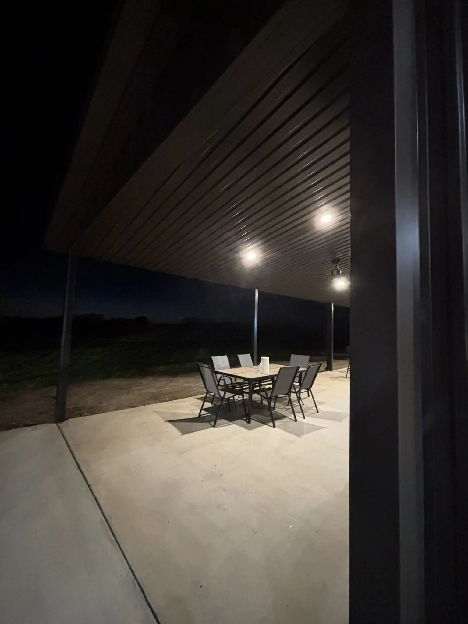 Covered patio lit up at night — built by Rodriguez Metal Buildings, Central Texas