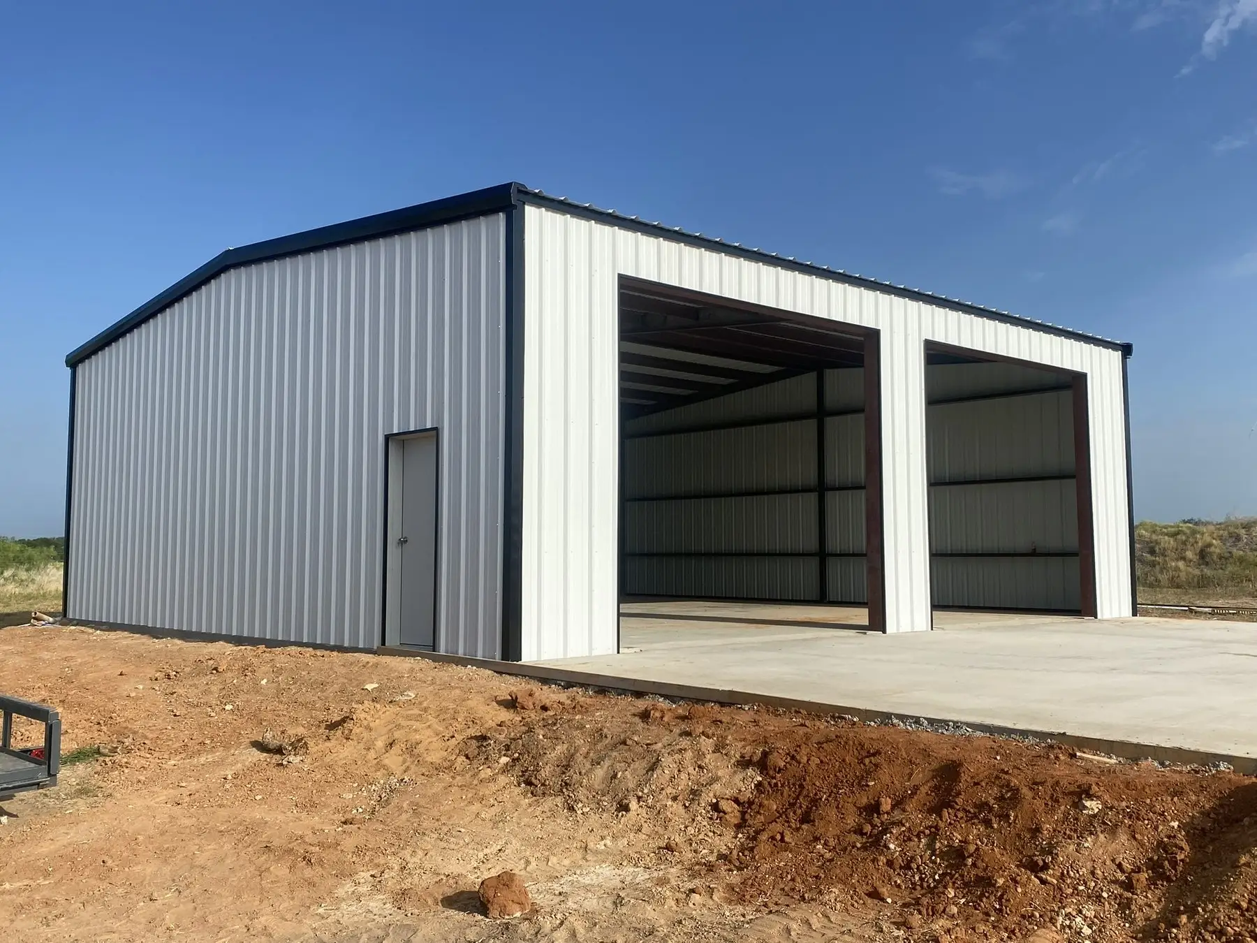 Tan shop with twin roll-up doors — built by Rodriguez Metal Buildings, Central Texas
