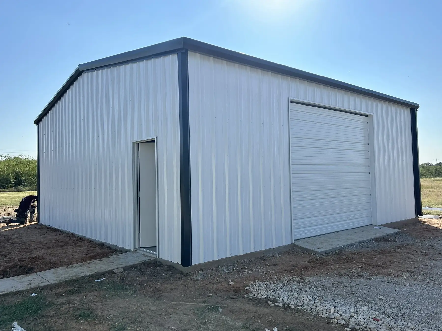 White shop with a single roll-up door — built by Rodriguez Metal Buildings, Central Texas