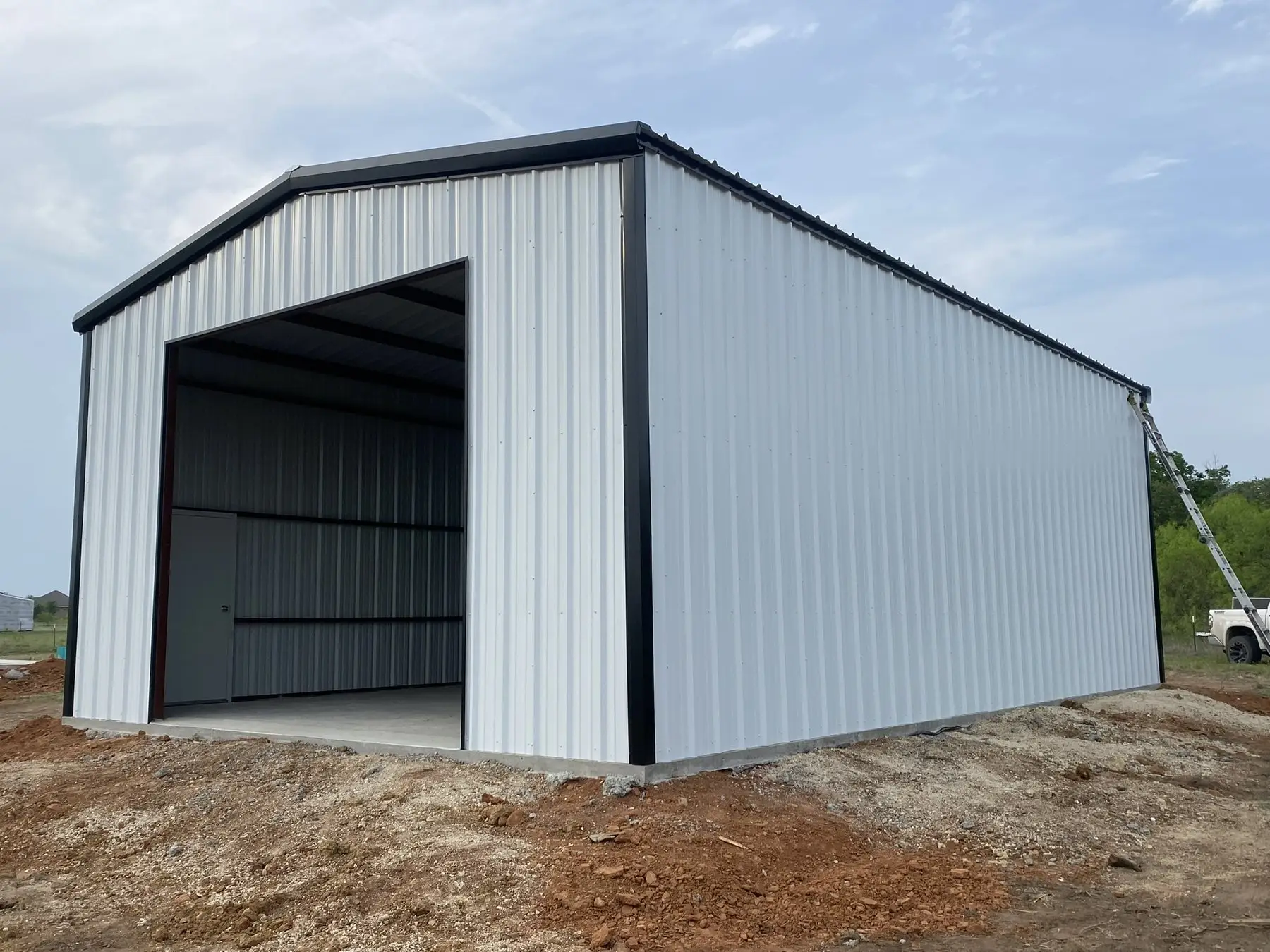 Tall white shop with an oversized opening — built by Rodriguez Metal Buildings, Central Texas